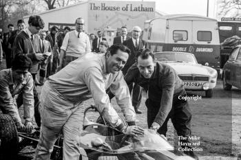 Driver Jack Brabham and designer Ron Tauranac push the Brabham Honda through the paddock at the Oulton Park Spring International meeting in 1965. The car was making its debut and Brabham offered to withdraw it from the race due to lack of speed (14mph slower on the straight than Graham Hill's Brabham BRM) but eventually it did start, lasting until lap 17. 
