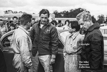 Graham Hill and John Coombes talk to mechanics in the paddock, Oulton Park Gold Cup meeting, 1964.
